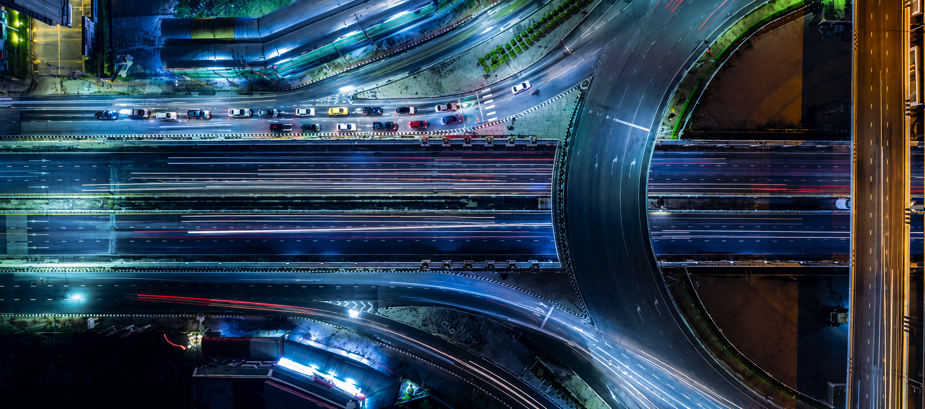 Aerial night view of a busy highway interchange with light trails