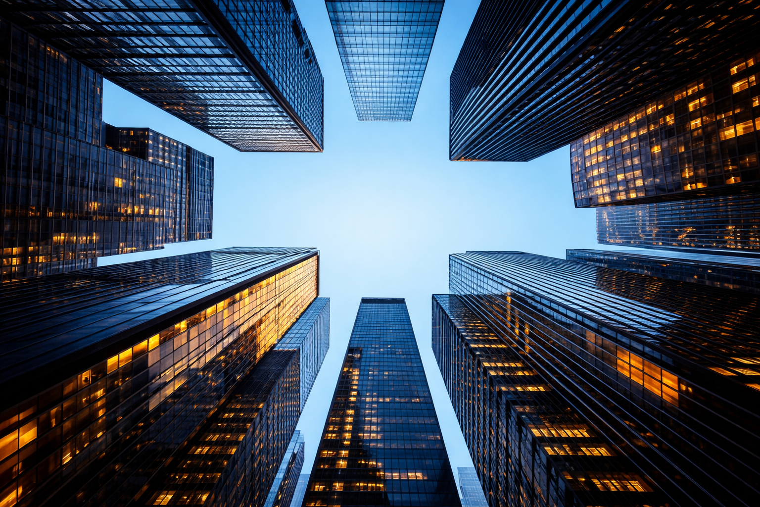 Upward view of illuminated financial district skyscrapers at dusk